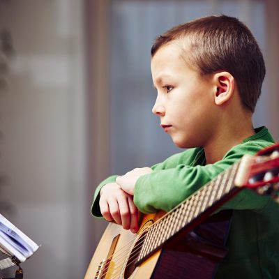 Little boy is playing the guitar at home