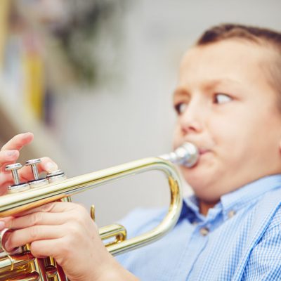 Little boy is playing the trumpet at home